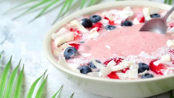 Berry smoothie kom met aardbeien, bosbessen en kokosnoot. Eet smoothie bowl met lepel. — Stockvideo