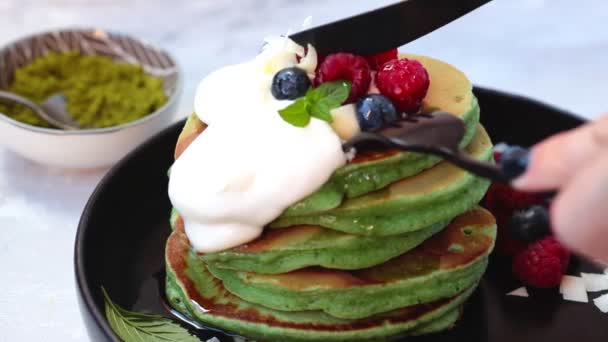 Grüne Matcha-Pfannkuchen mit Beeren auf schwarzem Teller schneiden. — Stockvideo