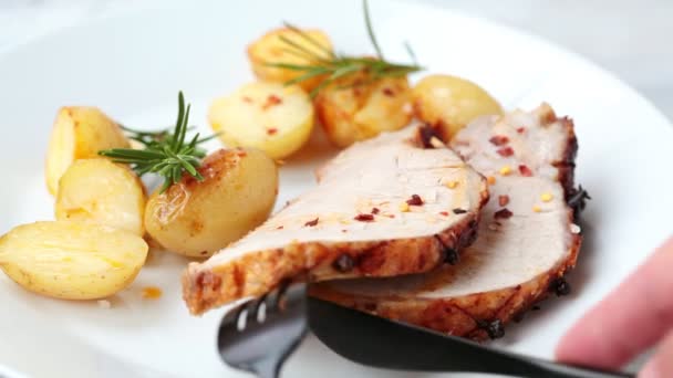 Potong sepotong daging babi panggang dengan kentang di piring putih, latar belakang abu-abu. — Stok Video