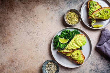 Avokado tostları ve gri tabakta tohumlar..