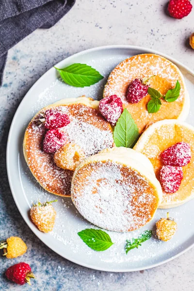 Japanese fluffy pancakes with raspberries in a gray plate, gray background. Japanese cuisine concept.