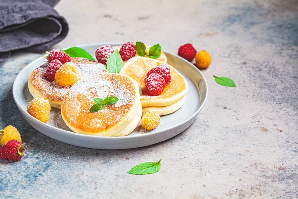 Japanese fluffy pancakes with raspberries in a gray plate, gray background. Japanese cuisine concept.