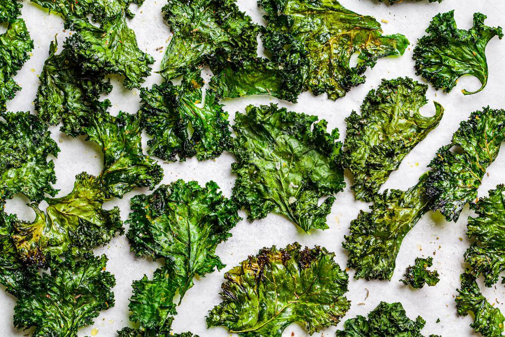 Green kale chips with salt on white background. Healthy vegan food concept.