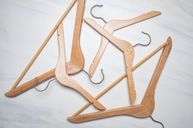 Boş ahşap elbiseler beyaz mermer arka planda asılı. Üst görünüm, boşluğu kopyala. Giyim mağazası ve indirim konsepti.