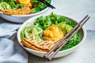 Buda kasesi kabaklı makarna, ızgara tofu, guacamole, tatlı patates humus ve sebze, gri arka plan.