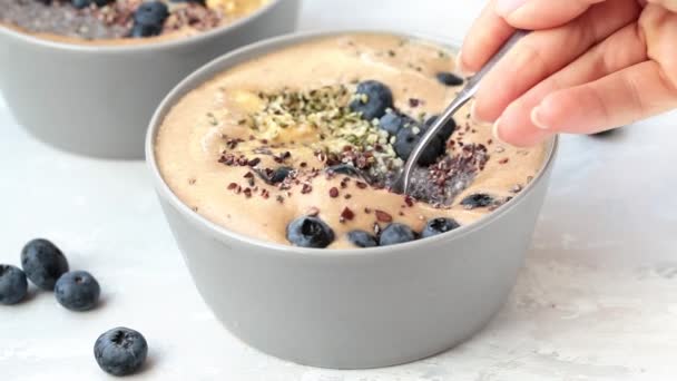 Petit déjeuner végétalien - bol de smoothie au chocolat avec pudding au chia, beurre d'arachide et baies dans un bol gris — Video