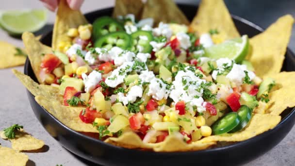 Mexican street corn salad with cheese and nachos chips in black plate. — Stock Video