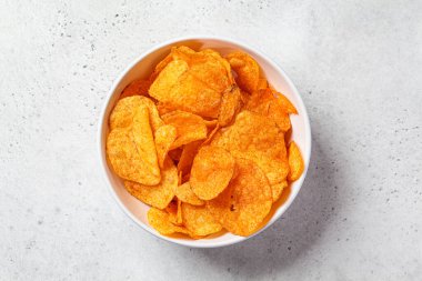 Beyaz kasede, gri arka planda baharatlı patates cipsi. Fast food konsepti.