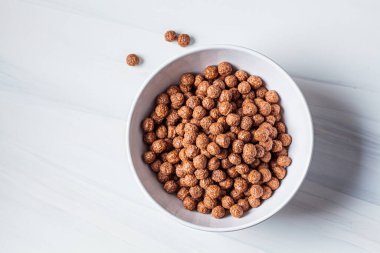 Çikolata topları beyaz arka planda beyaz bir kasede mısır gevreği. Kahvaltı konsepti..