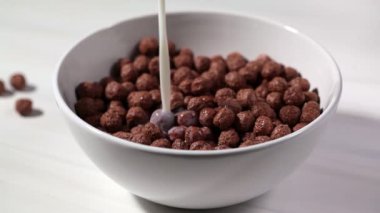 Çikolata topları, beyaz arka planda sütlü mısır gevreği. Kahvaltı konsepti..