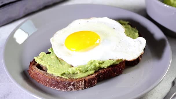 Matlagning avokado toast med ett ägg på grå platta. — Stockvideo