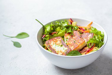 Izgara halloumi peynirli yeşil salata, beyaz kasede pancar ve havuç. Diyet gıda konsepti.