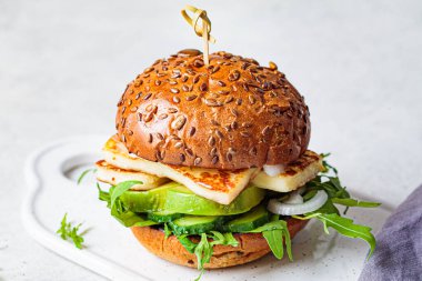 Avokado kamaları ve roka ile kızarmış halloumi burger. Vejetaryen gıda konsepti.