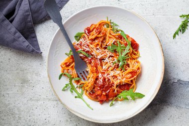 Büyük beyaz bir kasede domates soslu makarna, peynir ve roka. Geleneksel İtalyan mutfağı kavramı.