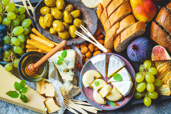 Cheese plate served with fruits, honey and snacks. Assorted cheese background.