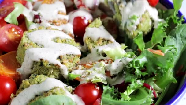Salada de falafel com legumes assados, molho de tahini e tomates em tigela branca. — Vídeo de Stock