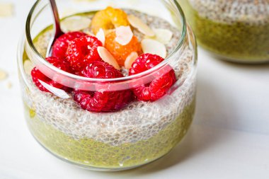 Beyaz arka planda, cam kavanozda kibrit çayı ve böğürtlenli Chia pudingi. Sağlıklı gıda konsepti.