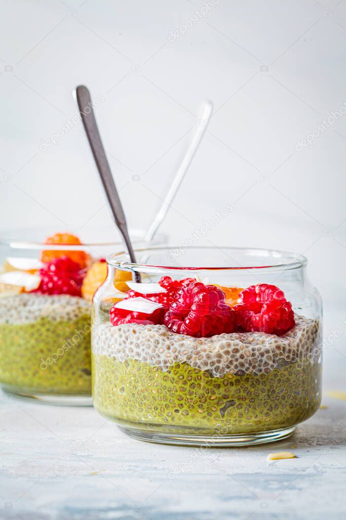 Chia pudding with matcha tea and berries in a glass jar, white background. Healthy food concept.