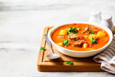 Tahtada beyaz bir tabakta sığır eti ve sebzeli çorba. Geleneksel et shurpa çorbası sebze ve otlarla.