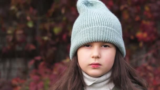 Злий дівчина-підліток тягне капелюх на обличчя в осінньому парку . — стокове відео