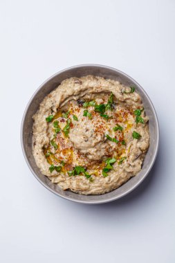 Baba ganoush - tahini ve baharatlı fırında patlıcan, beyaz arka planda gri bir kasede, üst manzara.