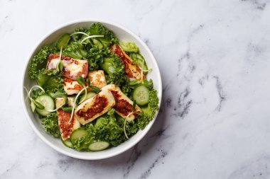 Salatalık, lahana ve yeşil yapraklı salata ve kızarmış halloumi peyniri..