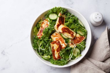 Salatalık, lahana ve yeşil yapraklı salata ve kızarmış halloumi peyniri..