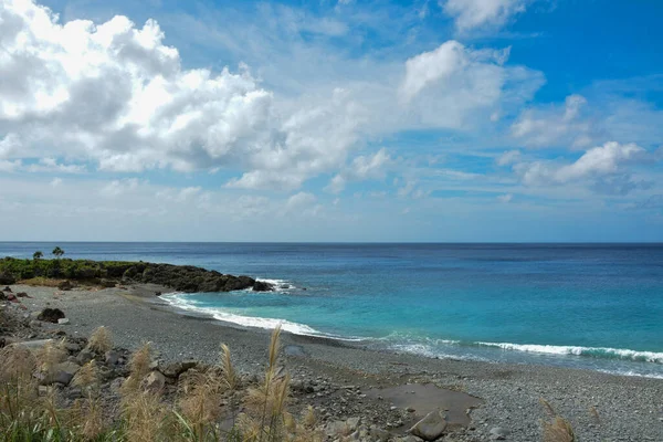 Serene Tidal Flat Landscape with Wooden Poles: A calm scene of shallow water covering a tidal flat, marked by rows of wooden stakes extending across the area.