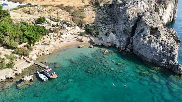 Kıyı boyunca demir atmış kayalık kayalıklarla ve yatlarla çevrili turkuaz bir hangarın insansız hava aracı görüntüleri. Seyahat, tatil, turizm ve Akdeniz yaşam tarzı kavramları için mükemmel bir deniz manzarası..