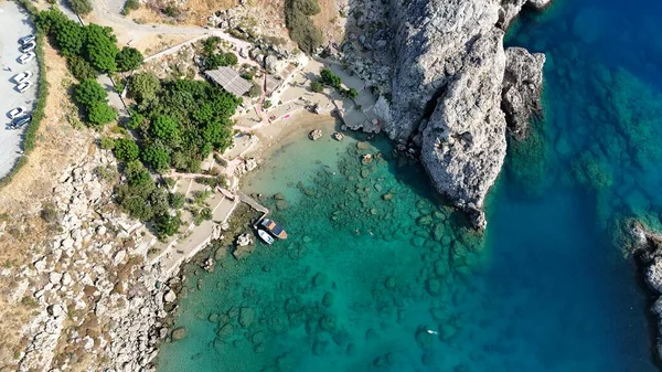 Turkuaz suları, kayalık uçurumları ve kıyıya yanaşmış tekneleri olan huzurlu bir körfezin nefes kesici manzarası. Akdeniz bölgesindeki yaz tatilleri, ada yaşam tarzı, turizm ve kıyı güzelliklerini resmetmek için mükemmel..