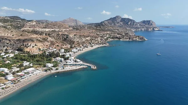 Rodos adasının insansız hava aracı manzarası, Yunanistan. Görüntüde mavi Ege Denizi, engebeli dağlar, kayalık kıyı şeridi ve manzaraya yerleşmiş geleneksel beyaz evler yer alıyor. Seyahat, turizm ve yaz tatili için mükemmel.
