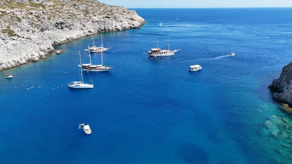 Anthony Quinn Körfezi 'nin kristal berrak turkuaz suyu, körfezde demirlemiş sayısız yat ve tekneler ve güneşli bir yaz gününde sıcak Akdeniz' de yüzen insanlar görüntüsü. Seyahat, tatil ve kıyı teması için ideal