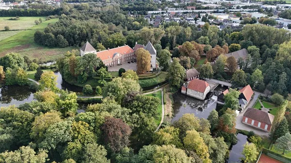 Almanya 'daki tarihi Rheda Wiedenbruck Kalesi' nin insansız hava aracı manzarası. Parlak bir yaz gününde yemyeşil ağaçlar ve sakin bir nehirle çevrili. Seyahat, mimari ve doğa kavramları için mükemmel.