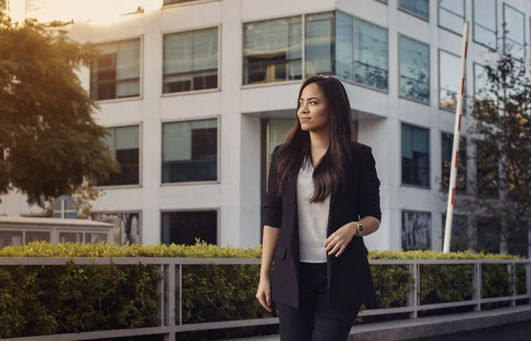 Beautiful hispanic business woman in suit walking outside with her office on a background golden hour, horizontal image, copy space