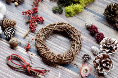The materials for making Christmas wreaths on the table include cane rings, pine cones and ribbons. Christmas decoration.