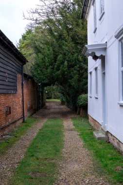 Saffron Walden, Essex, İngiltere - 25 Ocak 2024: Eski binaların arkasındaki tarlaya kemerli bir giriş oluşturan ağaçlarla çakıl yolu