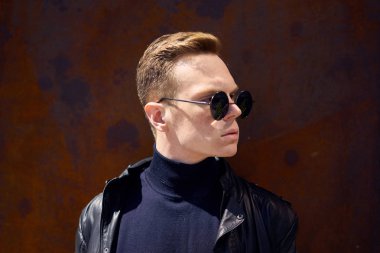 Genç yakışıklı olan paslı metal duvarın yanında