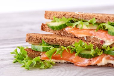 Sandviç ekmeği kızartır, kırmızı balık somon, taze yeşil salata yaprakları ve dilimlenmiş salatalık