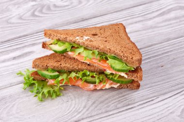 Sandviç ekmeği kızartır, kırmızı balık somon, taze yeşil salata yaprakları ve dilimlenmiş salatalık