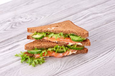 Sandviç ekmeği kızartır, kırmızı balık somon, taze yeşil salata yaprakları ve dilimlenmiş salatalık