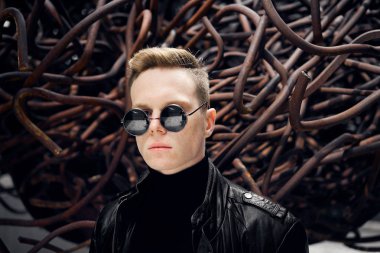 paslı demir arka plan üzerinde güneş gözlüğü yakışıklı bir genç adam portresi