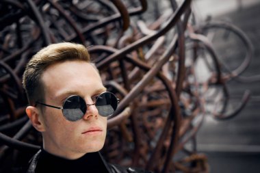 paslı demir arka plan üzerinde güneş gözlüğü yakışıklı bir genç adam portresi
