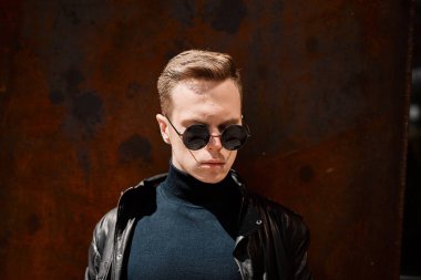 paslı demir arka plan üzerinde güneş gözlüğü yakışıklı bir genç adam portresi