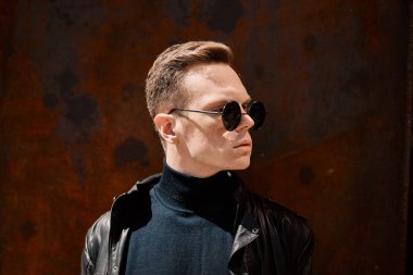 paslı demir arka plan üzerinde güneş gözlüğü yakışıklı bir genç adam portresi