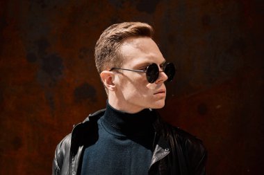 paslı demir arka plan üzerinde güneş gözlüğü yakışıklı bir genç adam portresi