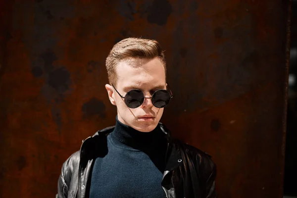 Portrait of a handsome young man in sunglasses on a rusty iron background — Stock Photo, Image