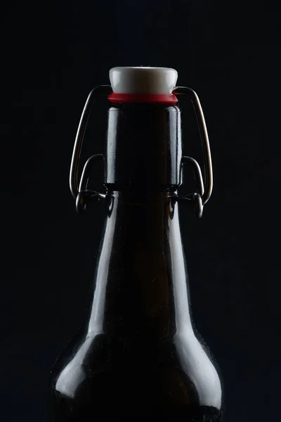Siyah arka planda kapağı koyu camlı bira şişesi. Stok Resim