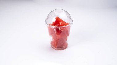 Beyaz arka planda plastik bir fincanda kırmızı greyfurt dilimleri