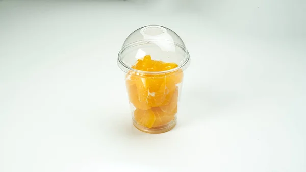 Pieces of tangerine in a plastic cup on a white background — Stock Photo, Image