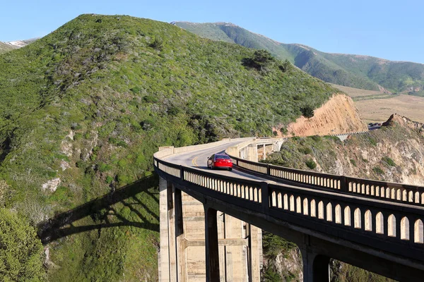 Bixby Bridge Overlooking the Pacific Ocean Along the Scenic Pacific Coast Highway 1 in Big Sur, California  Red Car Driving on a Road Trip Near Monterey, CA 